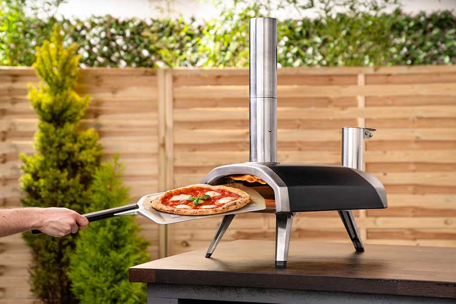 Fresh hot pizza being removed from Onni Frya outdoor pizza oven