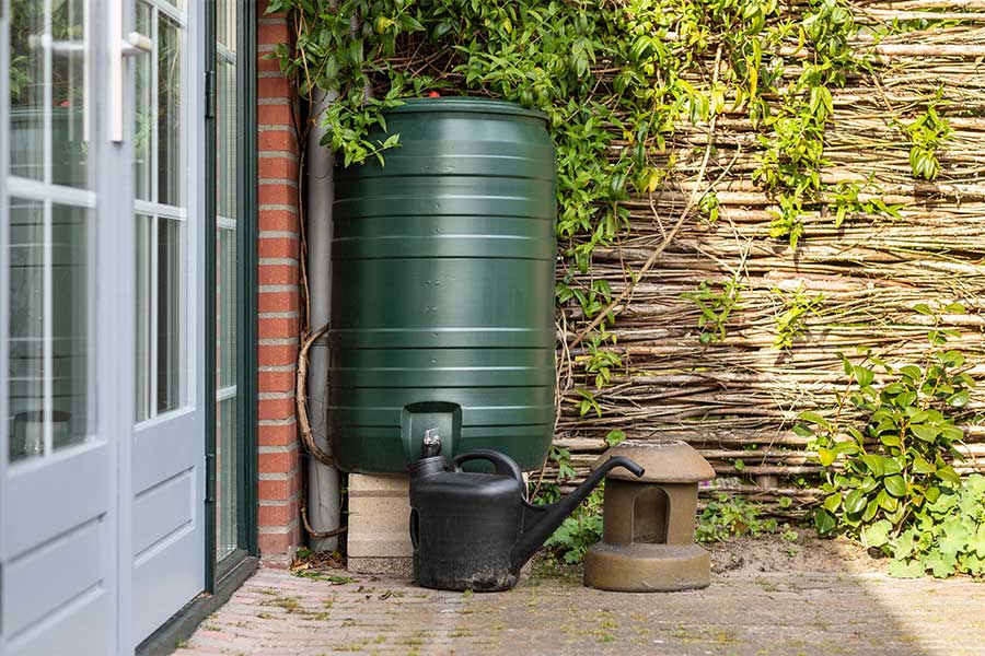 Rainwater harvesting with a water butt in the corner of a garden